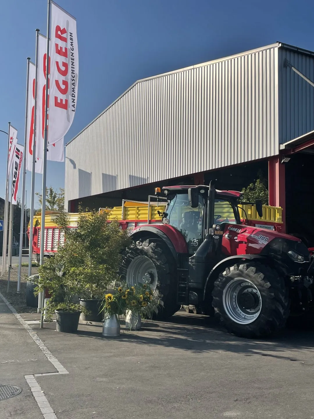 Traktor vor dem Firmensitz von Egger Landmaschinen, daneben die Firmenfahnen.