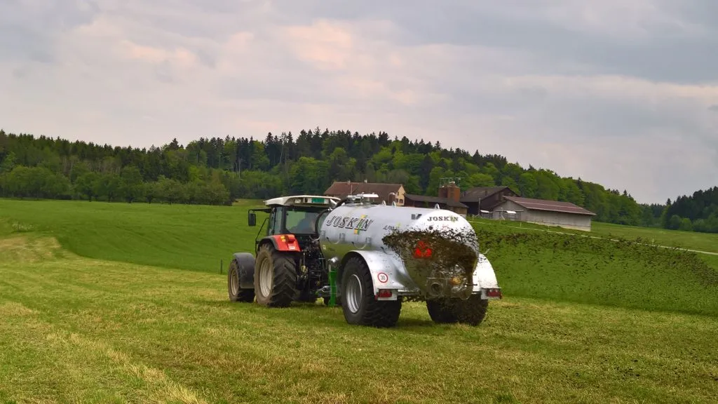 Traktor mit Güllefass im Einsatz auf dem Grünland.