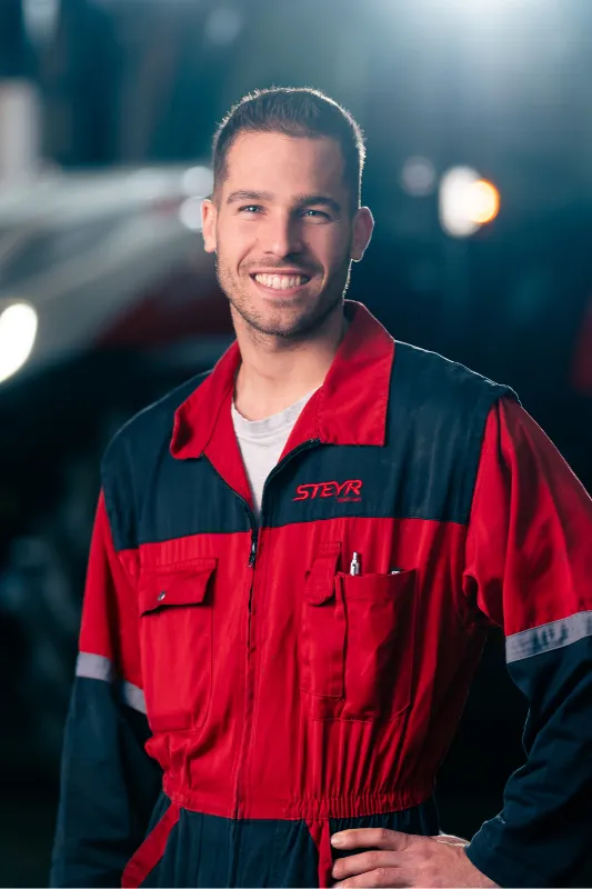 Pascal Markwalder im Arbeitsanzug vor einem Traktor.
