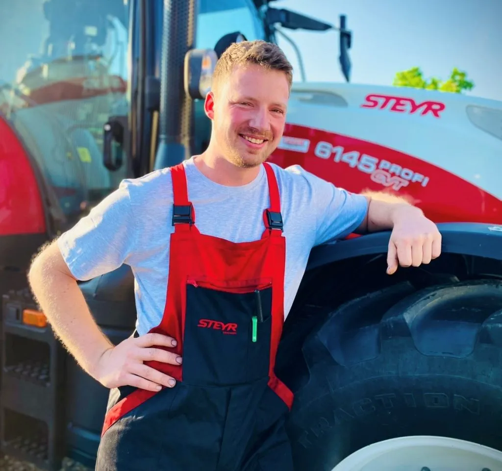 Silvan Stieger an einem Traktor angelehnt.